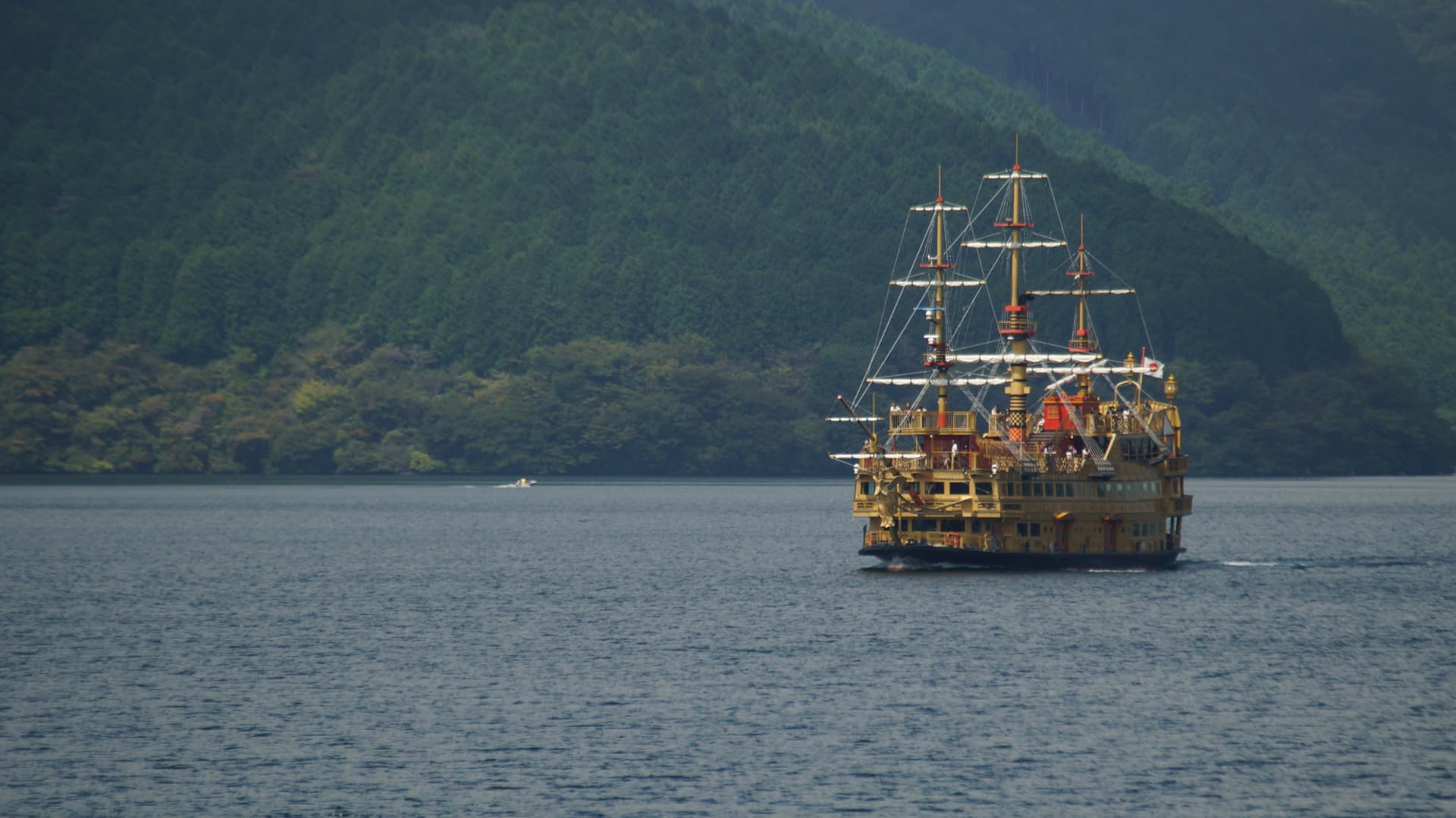 Sightseeing ship crossing Lake Ashi below forested hills in Hakone
